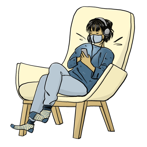Eine Frau mit kinnlangen, schwarzen Haaren sitzt in einem Sessel. Sie trägt einen Mundschutz und hört über Kopfhörer Musik.