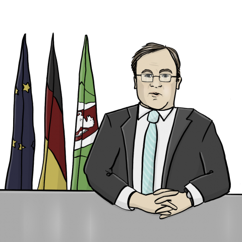 Armin Laschet in Anzug und Krawatte sitzt vor mehreren Flaggen an einem Tisch.