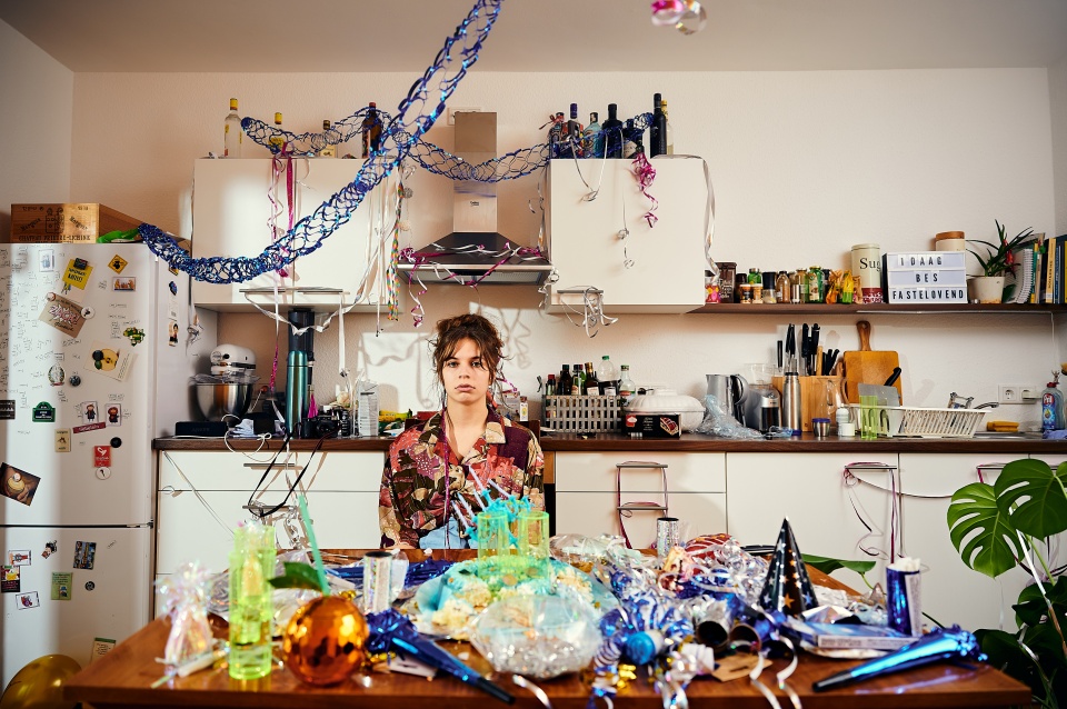 Eine Frau sitzt in einer mit Luftschlangen und Girlanden dekorierten Küche.