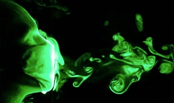 Eine Aufnahme unter Schwarzlicht zeigt Aerosole, die beim Niesen die Maske durchdringen