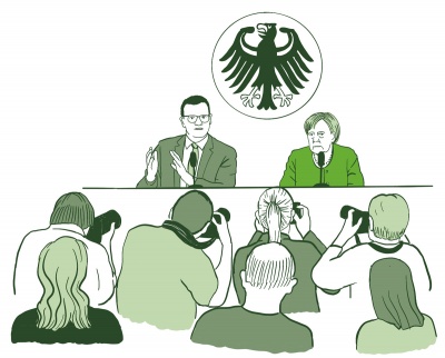 Angela Merkel und Jens Spahn sprechen vor Journalist:innen und Fotograf:innen in einem offiziellen Presseraum. Über den beiden sieht man den Deutschland-Adler.